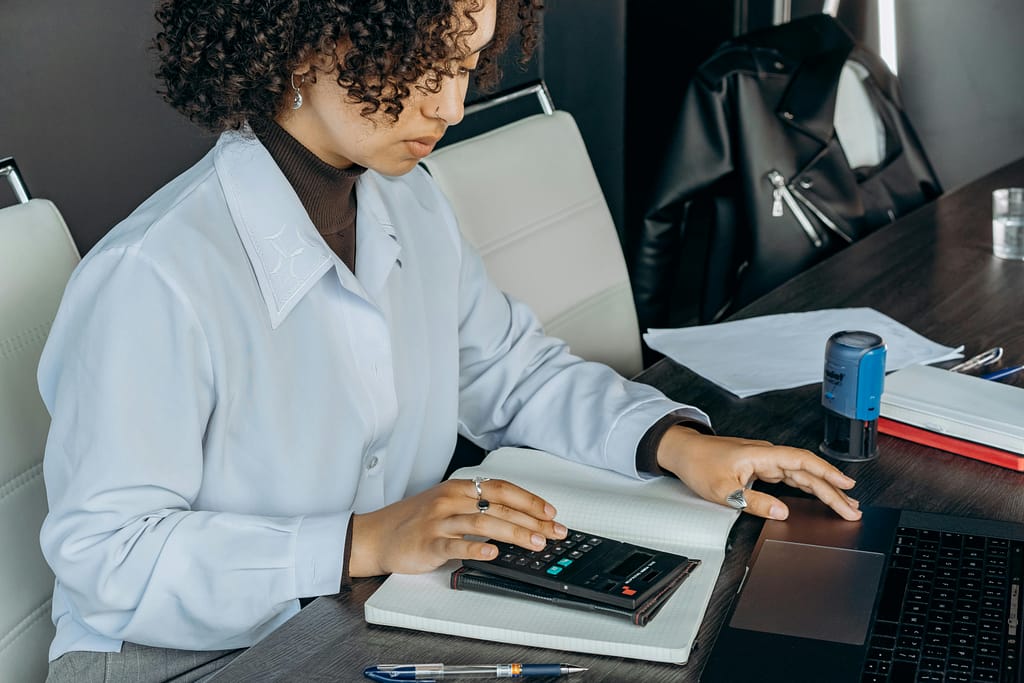 A woman in a white shirt calculating numbers on a calculator.